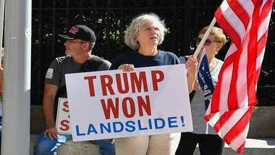 Trumpers holding signs saying, Trump won! By a landslide